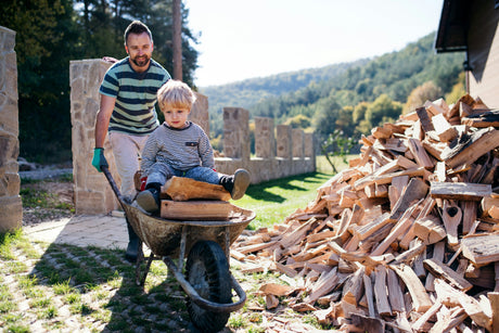 Vater und Kind transportieren Brennholz für den Kaminofen